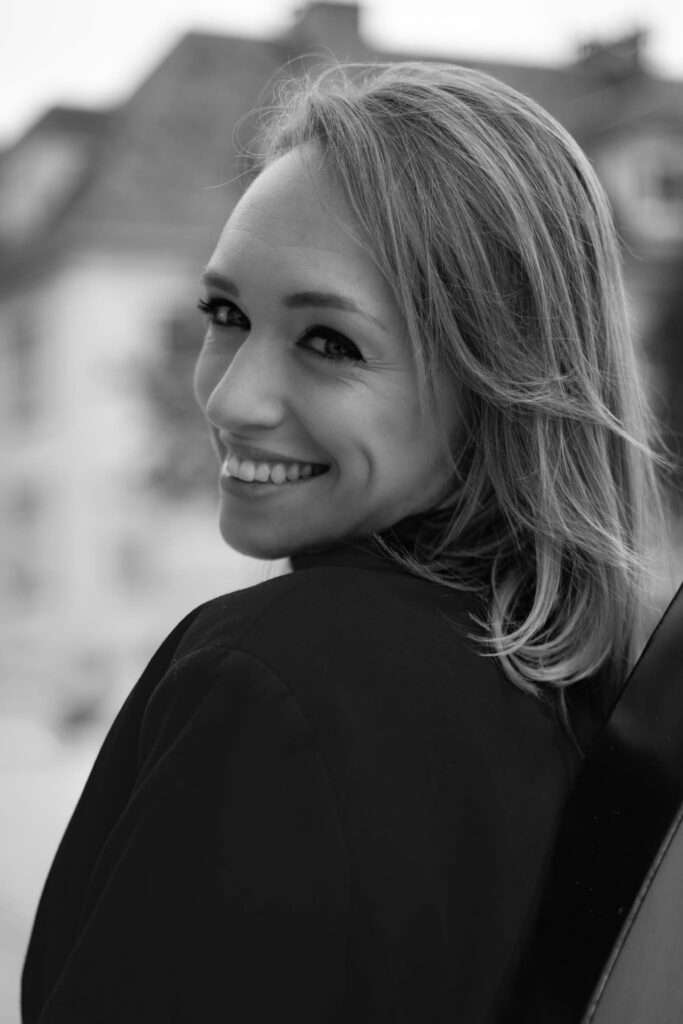 Portrait en noir et blanc d'une femme souriante regardant par-dessus son épaule