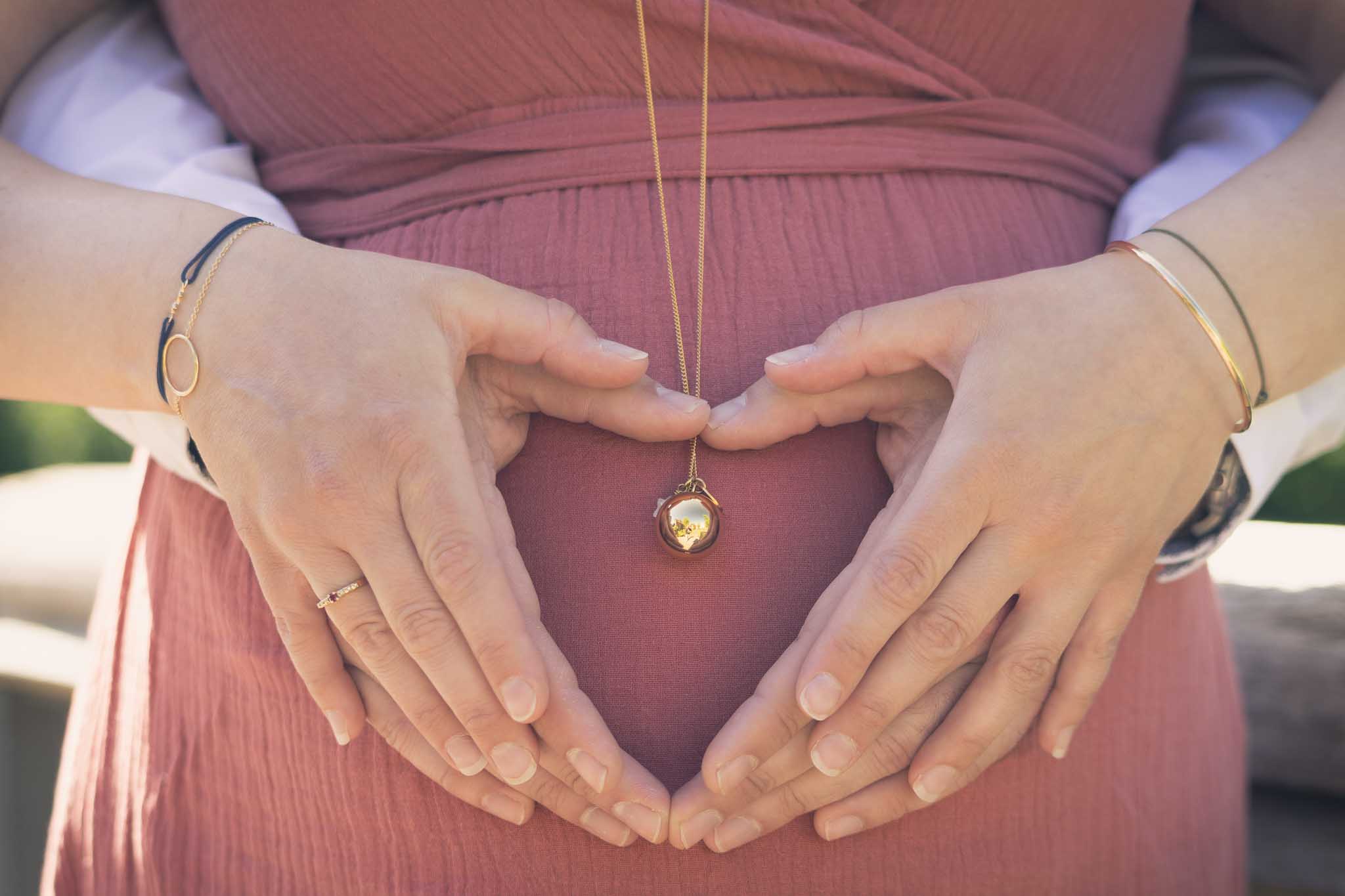 Mains en cœur sur ventre de future maman – séance grossesse